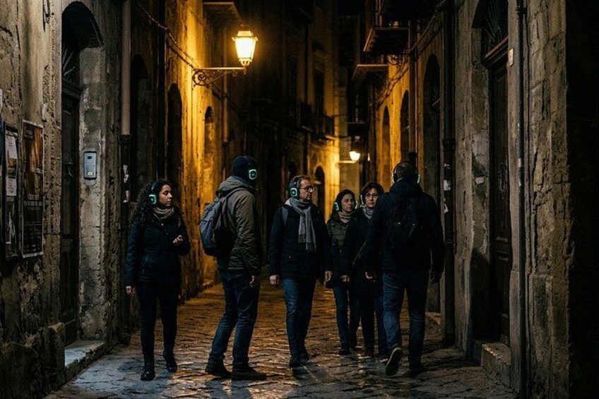 A narrow alleyway with stone walls, a cobblestone path, and a warm light source at the end. 4