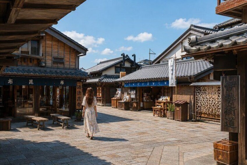 A traditional Japanese courtyard with wooden buildings, stone flooring, and a person in a white dress walking. 2