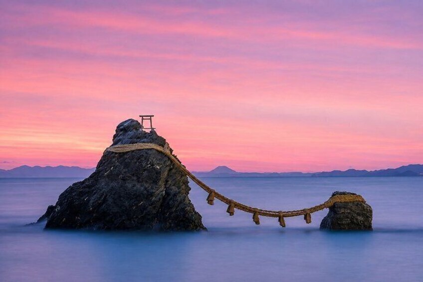 A rock formation with a wooden structure on top, connected by a rope to another rock. 1