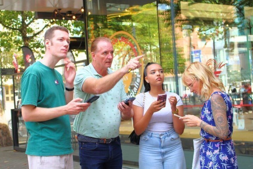 People standing on a sidewalk, looking at their phones. 1