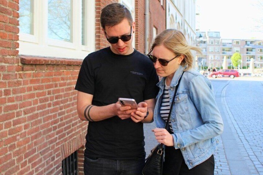 Two people standing on a brick sidewalk, one holding a smartphone. 2