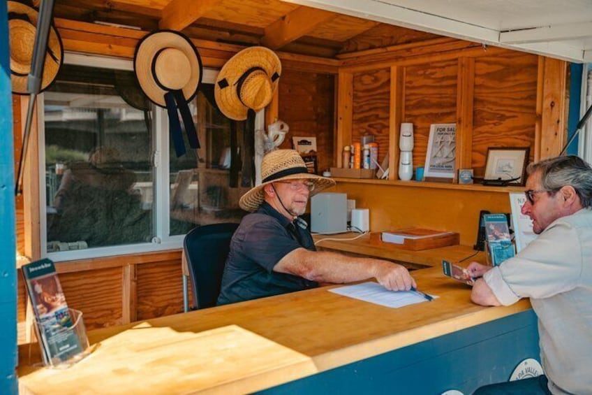 A wooden interior with a counter, hats hanging on the wall, and a window. 3