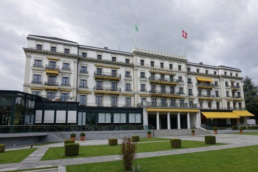 A multi-story building with balconies, a flag, and a well-maintained lawn. 5