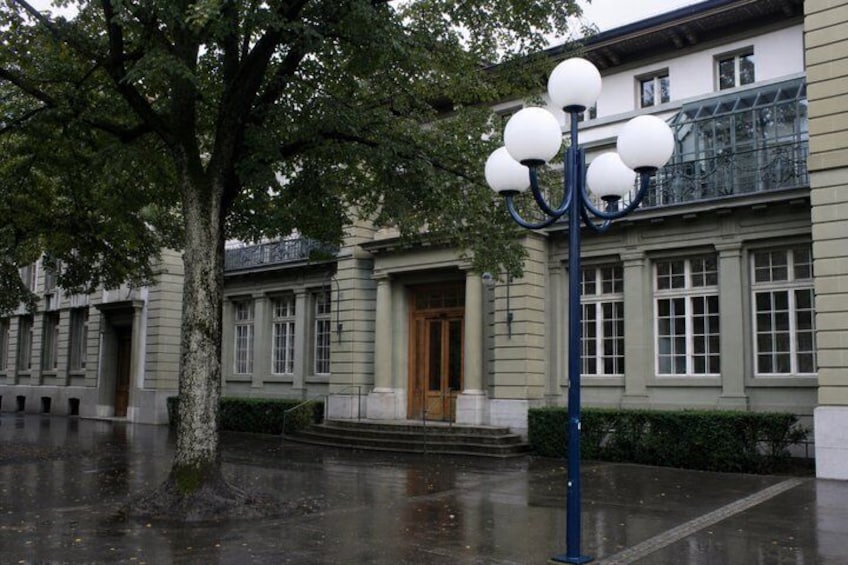 A building with a large tree, a blue street lamp, and a wet ground. 4