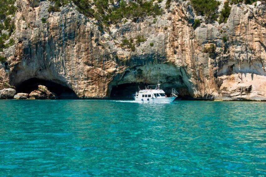 A boat near a rocky coastline with a cave entrance. 4