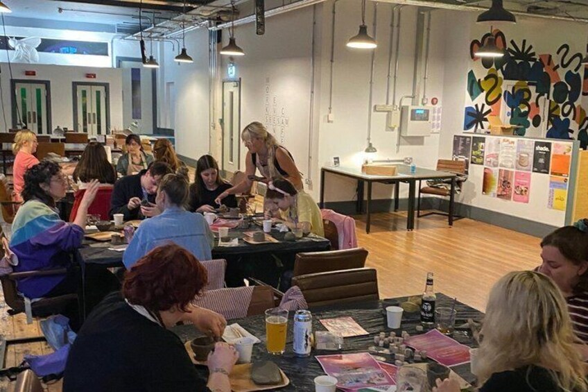 A group of people sitting at tables in a cafe with a colorful abstract mural on the wall. 5