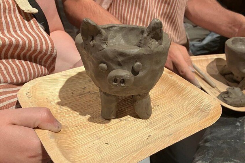 A person holding a clay piggy bank on a wooden tray. 2