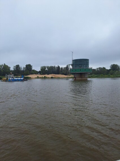 A river with a boat and a green structure on the bank. 2