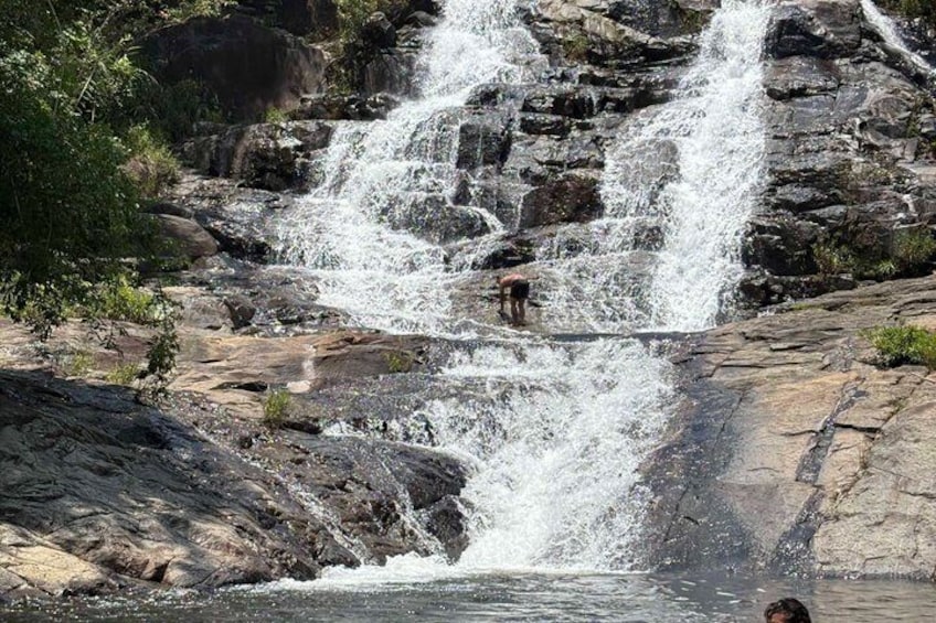 A waterfall cascading over rocks, with a person standing at the base. 1