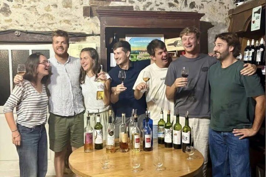A group of people standing around a table with wine bottles and glasses. 5