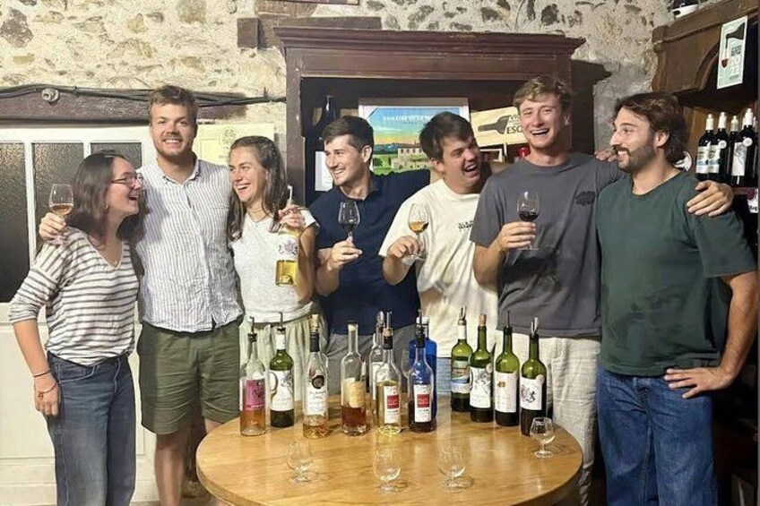 A group of people standing around a table with various bottles of wine. 3