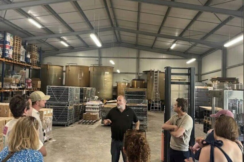 A group of people in a warehouse with shelves stocked with boxes and metal containers. 2