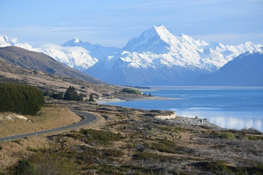 A winding road, a lake, and snow-capped mountains in the background. 4