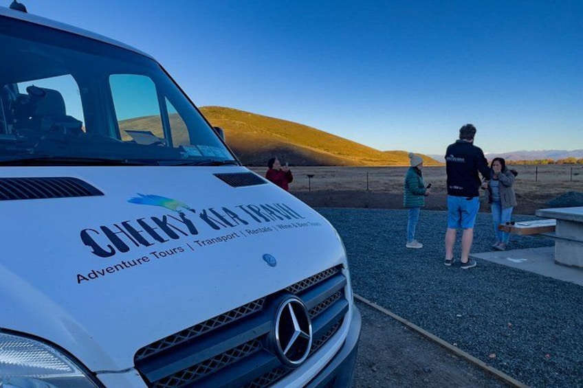 A white vehicle with 'CHEKY'S ADVENTURE TRIPS' branding, parked with people standing nearby. 2