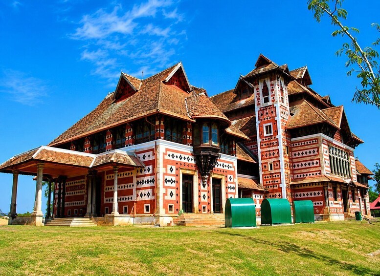 A large, ornate building with a steeply pitched roof and multiple chimneys, surrounded by a well-maintained lawn. 2
