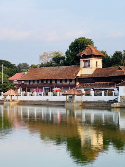 A traditional building with a clock tower, a reflection in the water, and a red-roofed structure in the foreground. 3