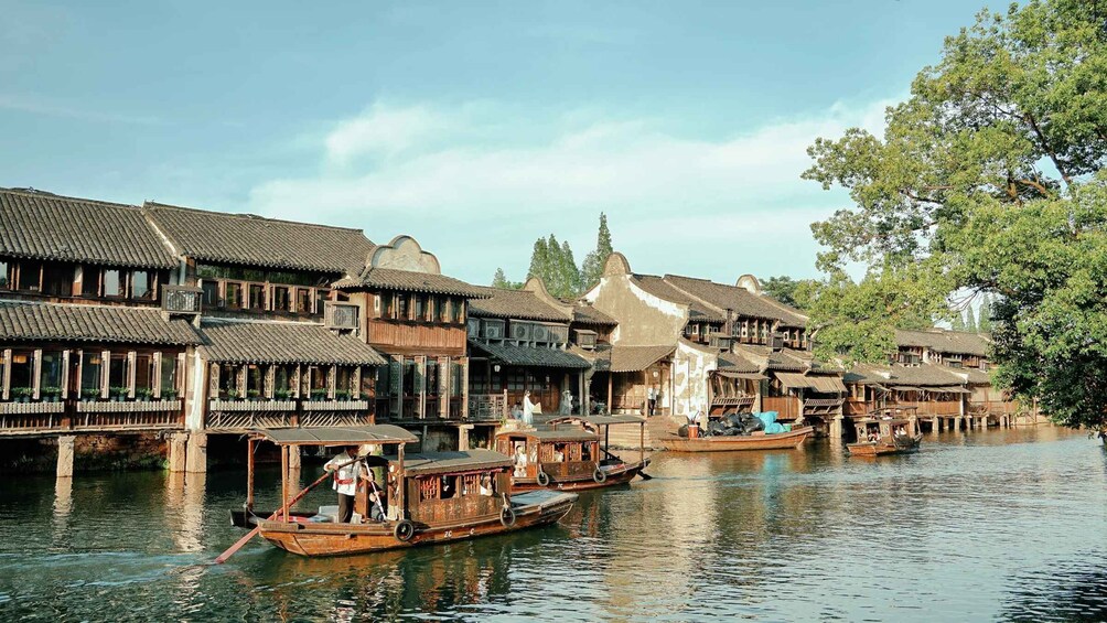 Traditional wooden buildings along a river with boats docked in front. 5