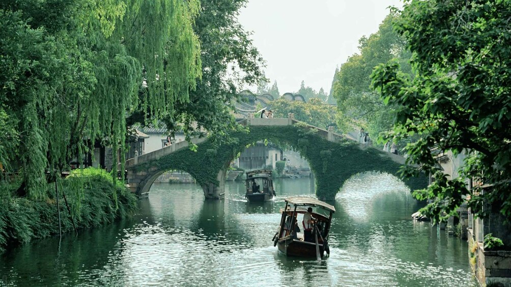 A traditional boat on a river, a stone bridge, and lush greenery. 4