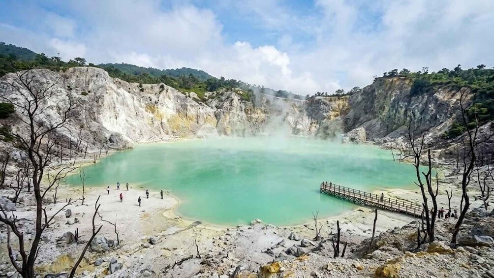 A geothermal hot spring surrounded by rocky terrain and sparse vegetation. 2