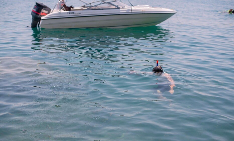 A swimmer in a body of water with a boat in the background. 1