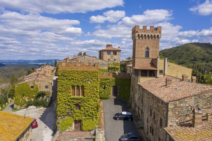 A historic town with stone buildings, a tower, and a road with cars. 5