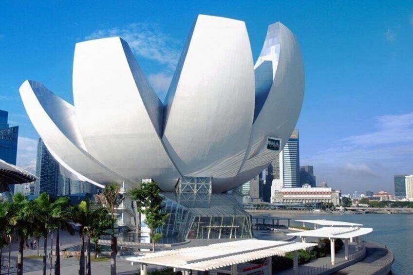 A modern architectural structure resembling a lotus flower, surrounded by a waterfront and urban buildings. 3