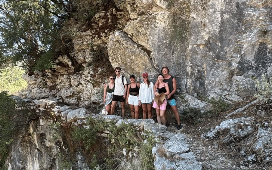 A group of people standing on a rocky cliff with a large rock formation in the background. 2