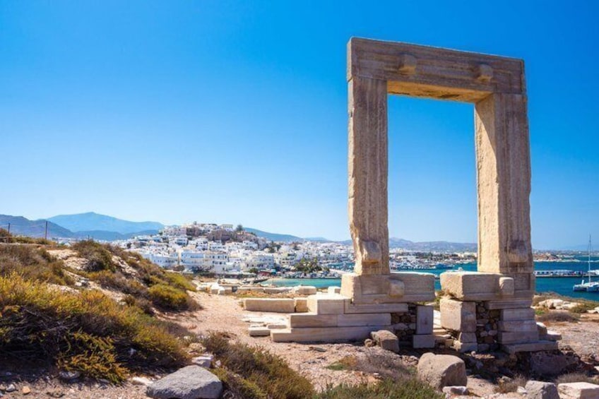 A stone archway, ruins, a coastal town, and a clear blue sky. 3
