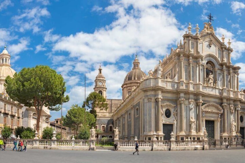 A grand historical building with domes and ornate architecture, surrounded by a spacious plaza with trees and a fence. 5