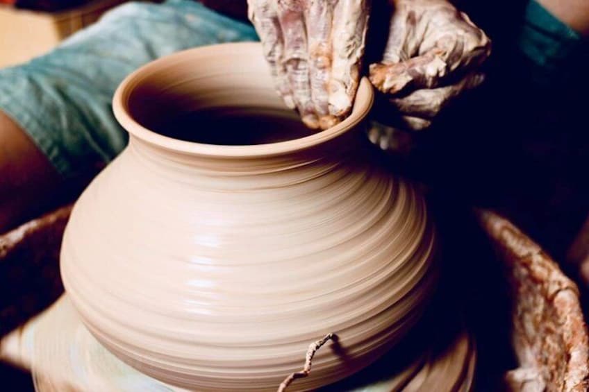 A person shaping a clay pot on a pottery wheel. 5