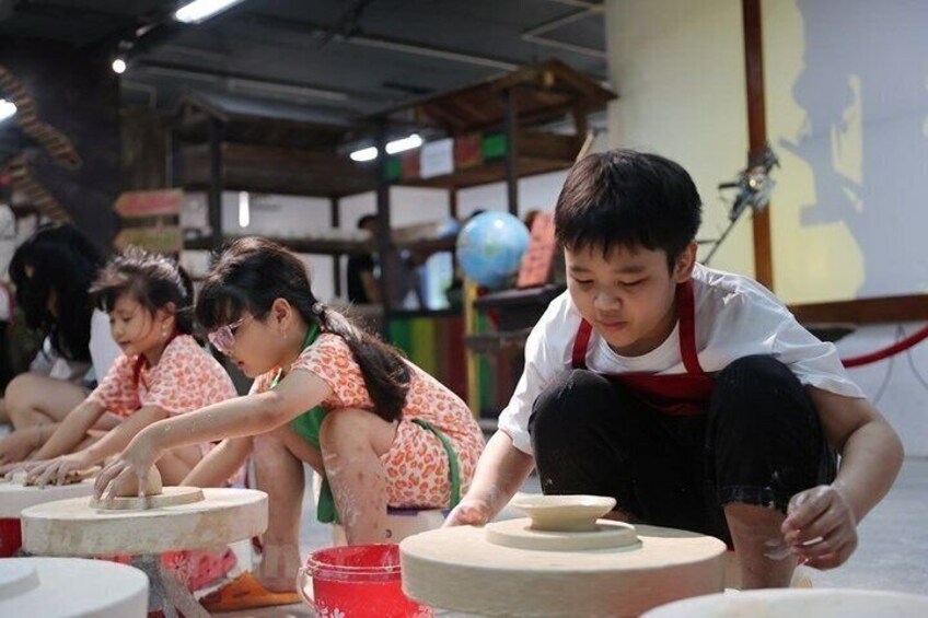 Children engaged in pottery making, with clay wheels and bowls on tables. 3