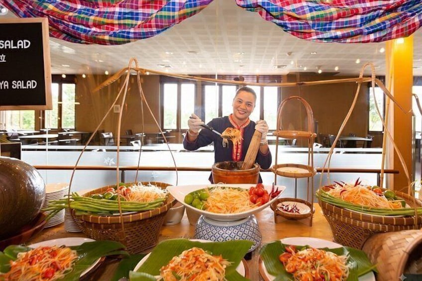 A buffet setup with various dishes displayed on plates and in baskets, a person serving food, and a sign indicating 'SALAD'. 2