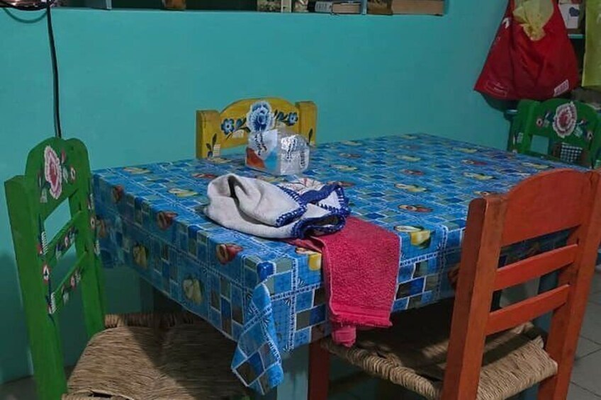 A small dining table with a blue tablecloth, a white bag, and a red cloth on it. 3