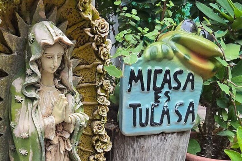 A statue of a robed figure with a sign that reads 'MICASA ES TULASA.' 4