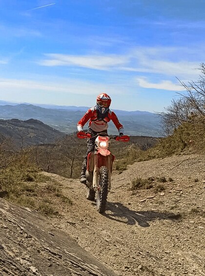 A person riding a dirt bike on a dirt path with a mountainous landscape in the background. 5