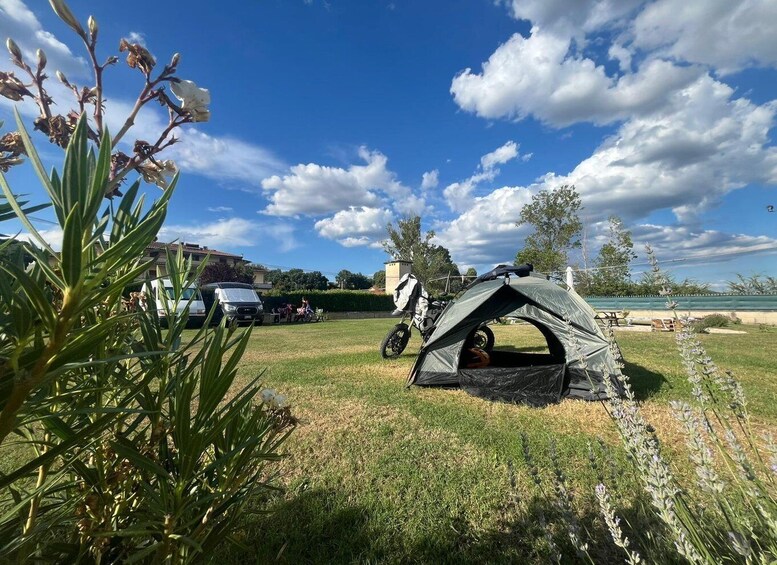 A camping site with a tent, a motorcycle, and a car. 2