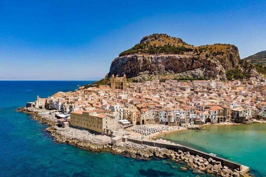 A coastal town with buildings, a rocky shoreline, and a prominent cliff. 1