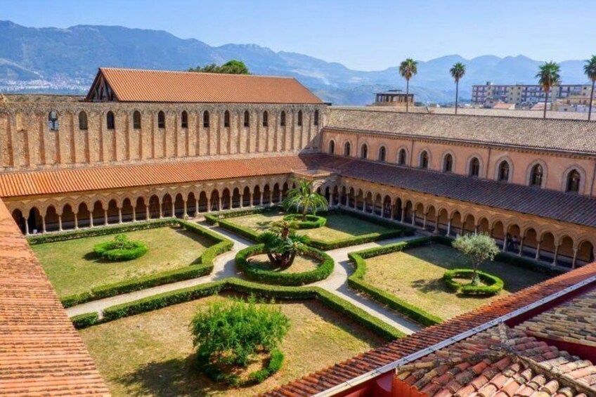 A courtyard with a central garden, arched walkways, and a building with a tiled roof. 3