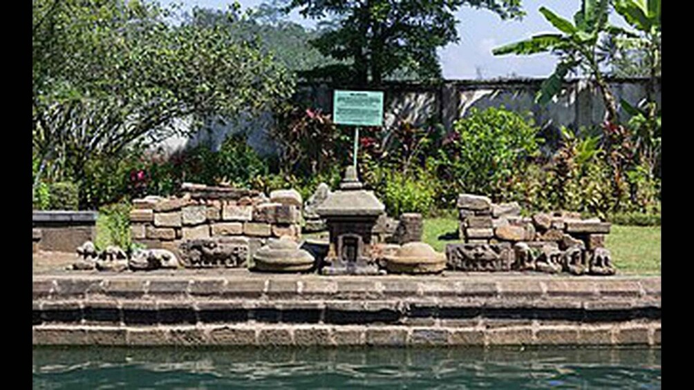 A stone structure with a sign, surrounded by water and greenery. 5