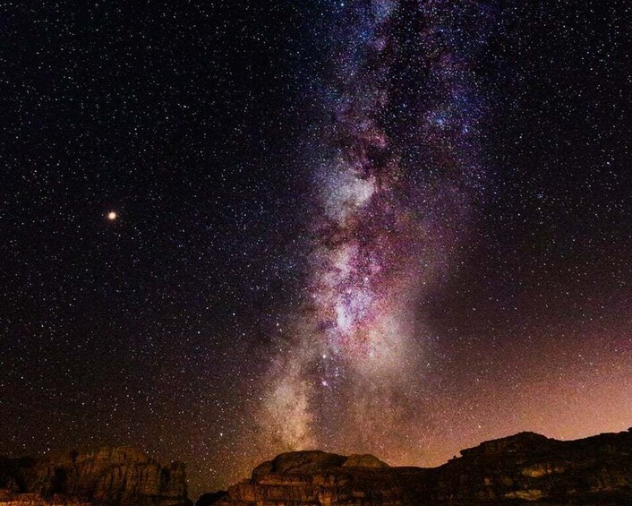 A starry night sky with the Milky Way galaxy and a silhouette of rock formations. 2