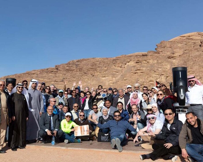 A group of people posing in front of a desert landscape with a large speaker. 4
