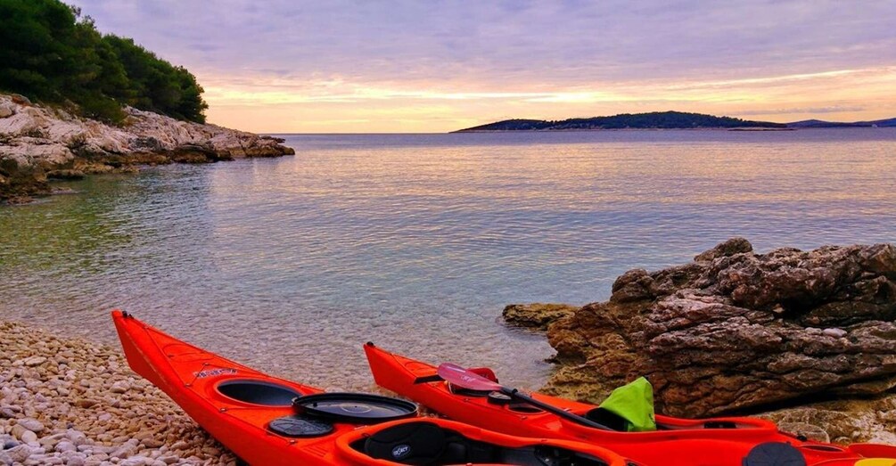 A calm lake with kayaks on the shore, surrounded by rocky terrain and distant hills. 2