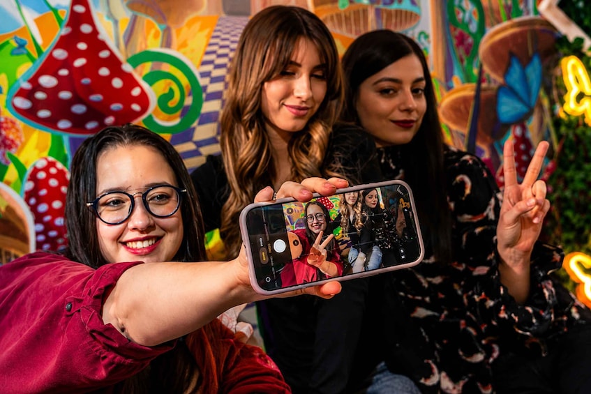 A person holding a smartphone with a selfie of three people. 2