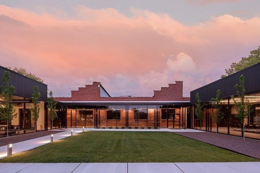 A modern building with a brick facade, large windows, and a well-maintained lawn. 1