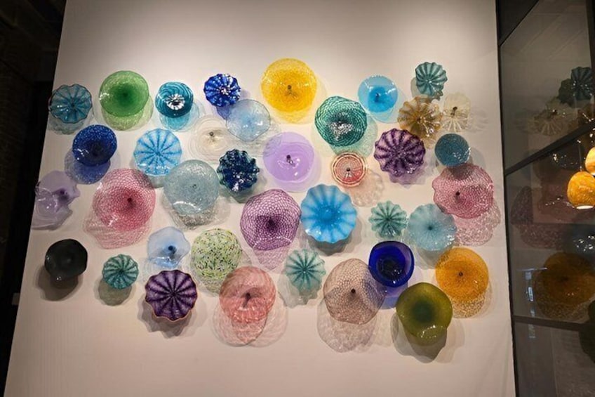 A collection of colorful glass art pieces displayed on a wall. 3