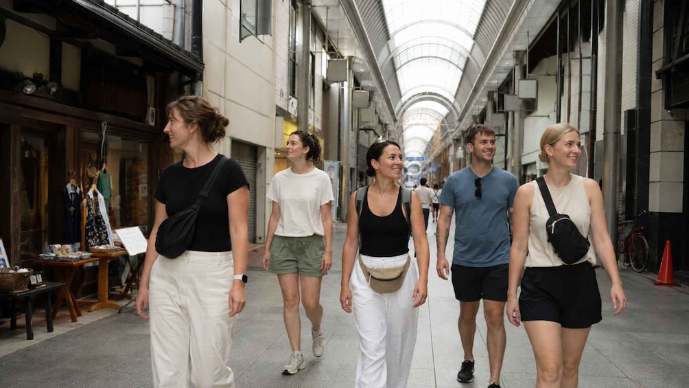 A group of people walking in a covered pedestrian area with shops on either side. 2