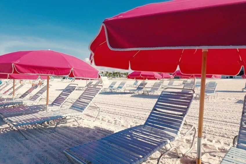 A beach with rows of sun loungers and red umbrellas. 3