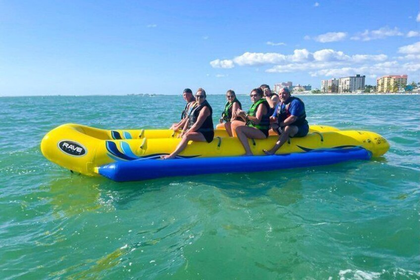 A group of people on a yellow inflatable raft in the ocean. 1
