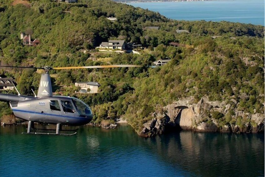 A helicopter over a body of water with a mountainous landscape in the background. 3