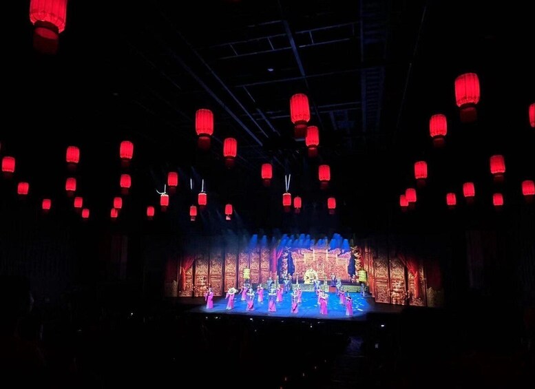 A stage with performers in traditional costumes, red lanterns hanging from the ceiling, and ornate stage decorations. 3